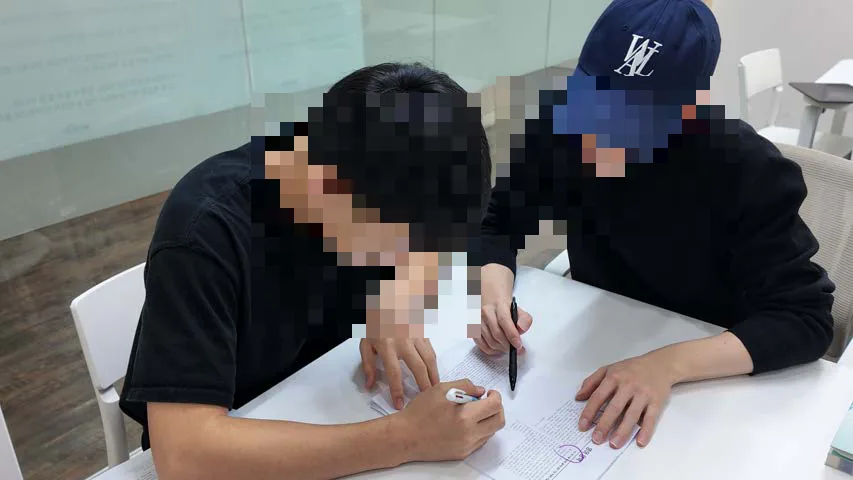 학생과 선생님이 한 책상에서 답안을 함께 보며 고치는 모습